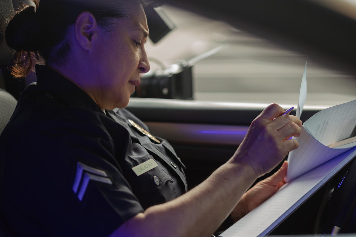 A female police officer sits in a patrol car