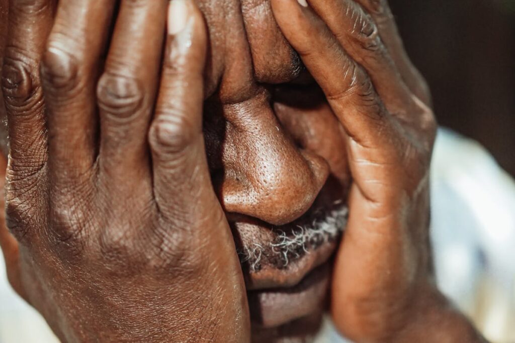 Man in White Shirt Covering His Face
